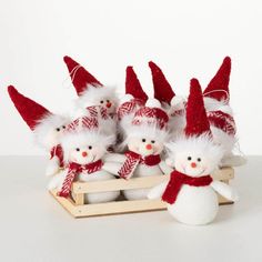 snowmen in red and white knitted hats are sitting on a sled