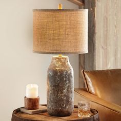 a table lamp sitting on top of a wooden table next to a brown leather couch