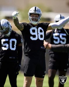 a football player holding his arms up in the air while standing next to other players