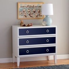 a blue and white dresser in a room with a painting on the wall behind it