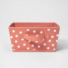 a pink and white polka dot fabric storage bin with handles on the front, side view