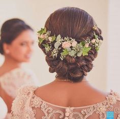 a woman with flowers in her hair is looking at herself in the mirror while wearing a wedding dress