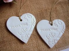 two white heart shaped tags with thank you written on them next to a pink flower