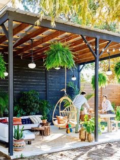 an outdoor living area with hanging plants and furniture on the patio, surrounded by greenery