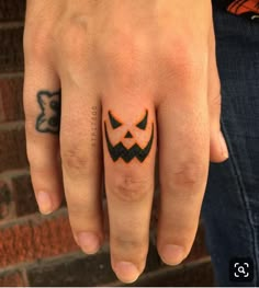 a person's hand with a tattoo on it and a jack o lantern ring