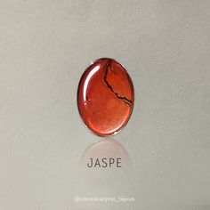 a red brooch with the word jaspe written below it on a white surface