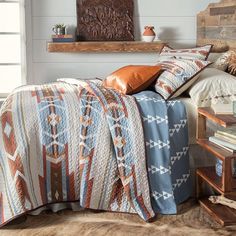 a bed with a blanket and pillows on top of it next to a wooden headboard