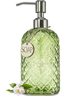 a green soap dispenser with a tag on it and flowers around it