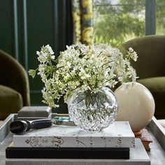 a glass vase filled with white flowers sitting on top of a book next to a pair of glasses