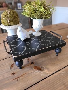 two white vases sitting on top of a black tray with moss growing out of it