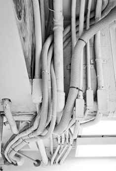 black and white photograph of multiple pipes attached to a wall in an electrical sub panel