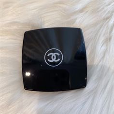 a chanel logo is shown on the side of a black box sitting on a white furnishing