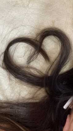 a woman laying on top of a bed with her hair in the shape of a heart