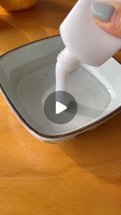 someone is pouring something into a bowl on a wooden table with apples in the background