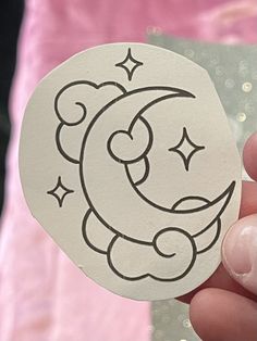 a person holding up a paper cut out of the moon with stars on its face