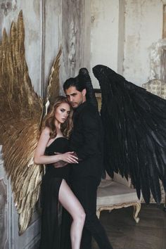 a man and woman dressed in black posing for a photo with an angel wings on their back