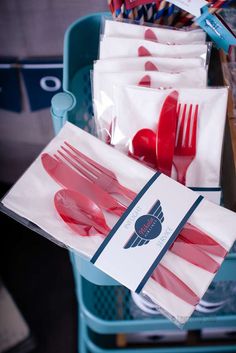 red and white plastic forks and spoons are in a bag on a chair with other items