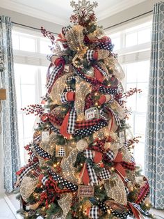 a christmas tree decorated with red, white and gold ribbons