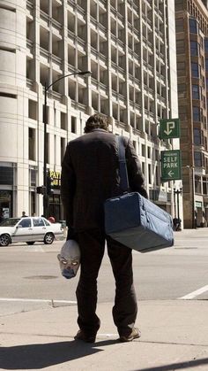 a man is walking down the street with his suitcases in hand and bags on his back