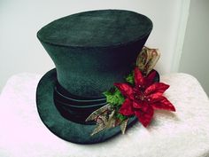 a green hat with a red flower on it sitting on top of a white table