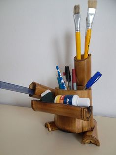 a wooden holder with pens, pencils and other items in it on a table