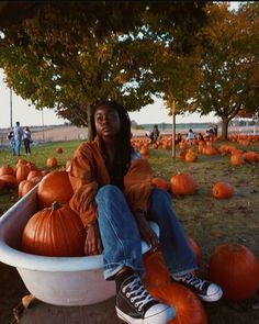 a woman sitting in a tub filled with pumpkins