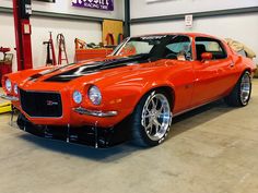 an orange muscle car parked in a garage