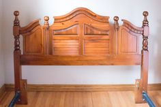 a wooden bed frame sitting on top of a hard wood floor next to a wall