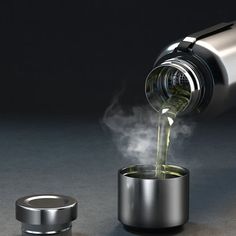 a person pouring something into a cup with steam coming out of it and an object in the background