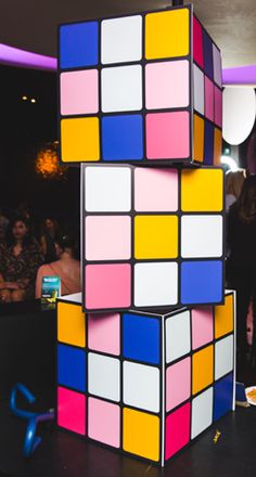 a rubik cube is stacked on top of each other with people in the background