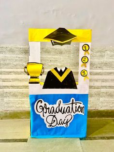 a paper bag with a graduation cap and gown on it sitting in front of a wall