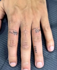 two fingers with tattoos on them, one has the creation of man and woman's hands