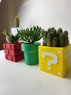 three different colored planters sitting on top of a white table next to each other