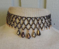 To bead this choker, I did netted weave using: twisted, bronze, bugle beads;  black and brass, size 10 and 11, seed beads, and bronze, faceted, Czech glass, drop beads.   Because I added an extender, the length is adjustable; starting at 31 cm. (12 1/4"), up to 47 cm. (18 1/2").  It closes with a black, lobster claw clasp. If you would prefer the tail loop up rather than dangle, just let me know at time of purchase, and I can easily add a hook. at at the end. The last photo shows more of my work.   If you don't see the listing in my shop, contact me and, chances are, if I don't have it in stock I can probably make a custom necklace for you. This is a simple version of the amazing collars made by Native-Americans, for centuries, up to the present.  To see some examples, go to the National M Elegant Evening Wear, Bugle Beads, Beaded Choker Necklace, Drop Beads, Black And Brass, Beaded Choker, Custom Necklace, Choker Necklaces, A Hook