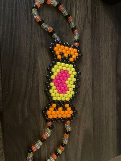 a beaded necklace with an orange, yellow and black cat on it's side