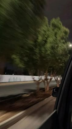 a car driving down the road at night with trees on both sides of the street