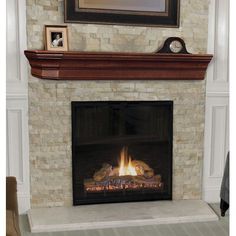 a fire place in a living room with a clock on the mantle and pictures above it