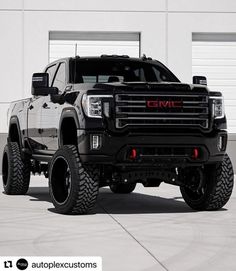 a large black truck parked in front of a garage