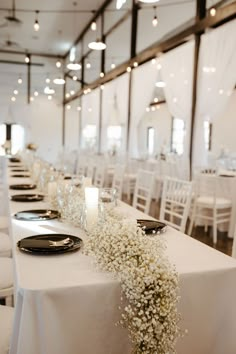 the tables are set with black plates and white linens, baby's breath