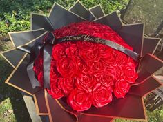 a large bouquet of red roses is sitting on a bench with a ribbon that says i love you so much