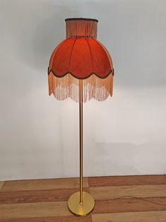 an orange lamp with fringe shade on wooden floor