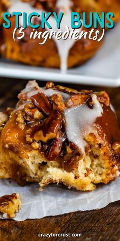 sticky buns with icing and pecans on top, sitting on a wooden table