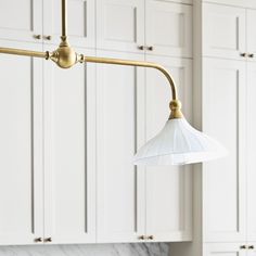 a kitchen with marble counter tops and white cabinets in the background, including an overhead light fixture