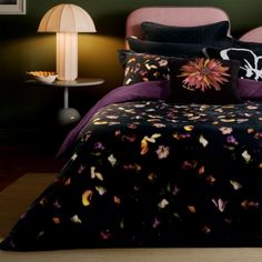 a bed with black and purple comforters in a green room next to two lamps