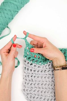 two hands crocheting the ends of a knitted bag