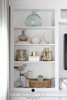 a white book shelf filled with lots of books and vases on top of it