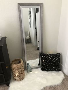 a mirror sitting on top of a white rug next to a black chest of drawers