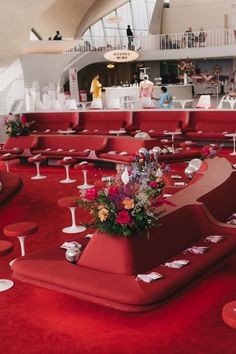 a room filled with lots of red chairs and tables covered in flower centerpieces