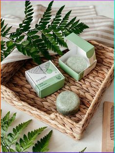 two soaps sitting on top of a wicker tray next to a green plant