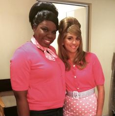 two women standing next to each other in front of a mirror